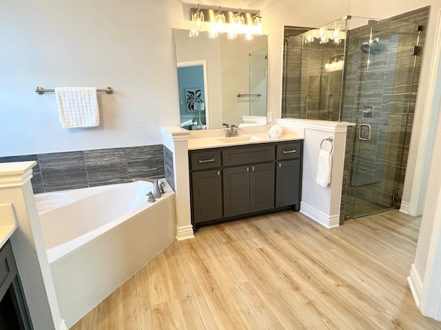 bathroom featuring a garden tub, a shower stall, wood finished floors, and vanity