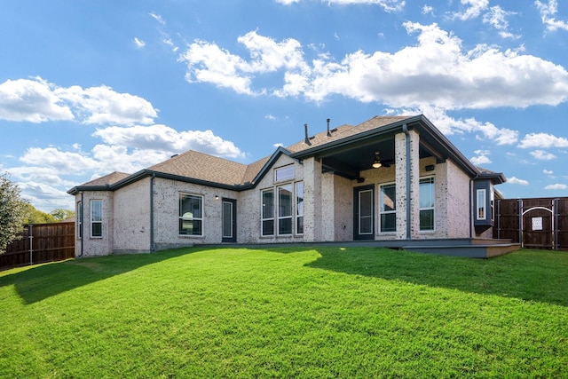 back of house with brick siding, a fenced backyard, ceiling fan, and a yard