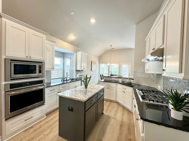 kitchen with white cabinets, under cabinet range hood, stainless steel appliances, and lofted ceiling