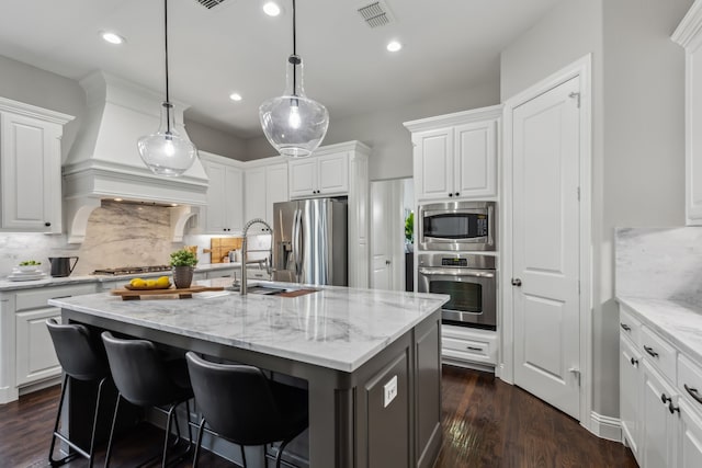 kitchen with visible vents, a kitchen island with sink, dark wood finished floors, white cabinetry, and appliances with stainless steel finishes