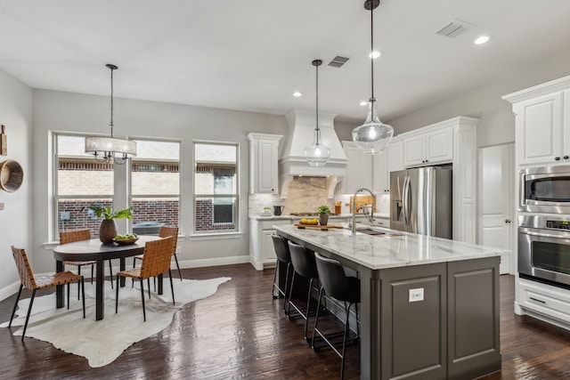 kitchen with visible vents, white cabinets, a sink, stainless steel appliances, and backsplash