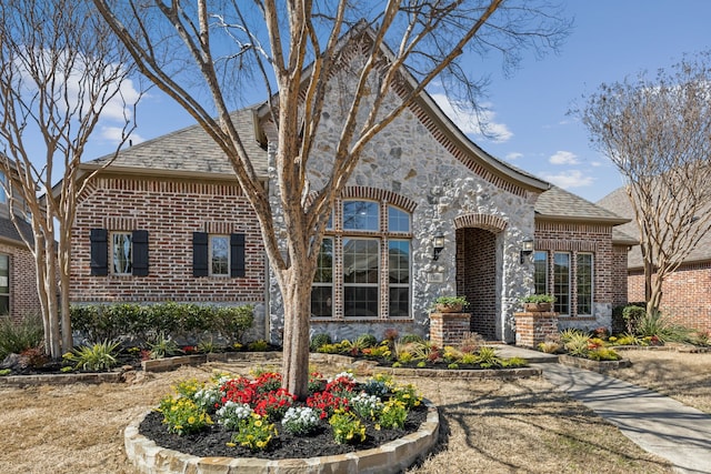 french country inspired facade featuring stone siding and brick siding