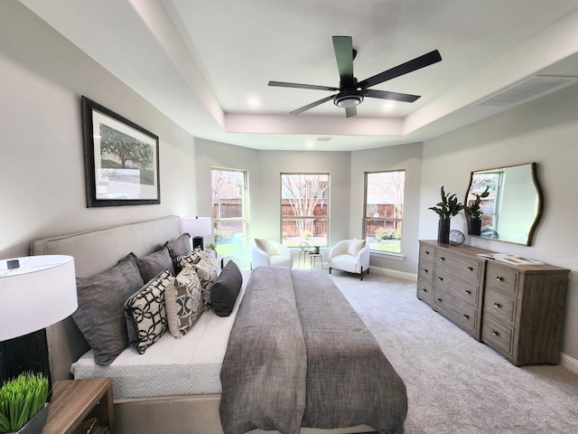 bedroom with visible vents, a tray ceiling, baseboards, and light colored carpet