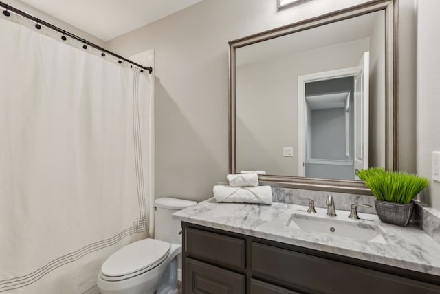 bathroom featuring curtained shower, vanity, and toilet