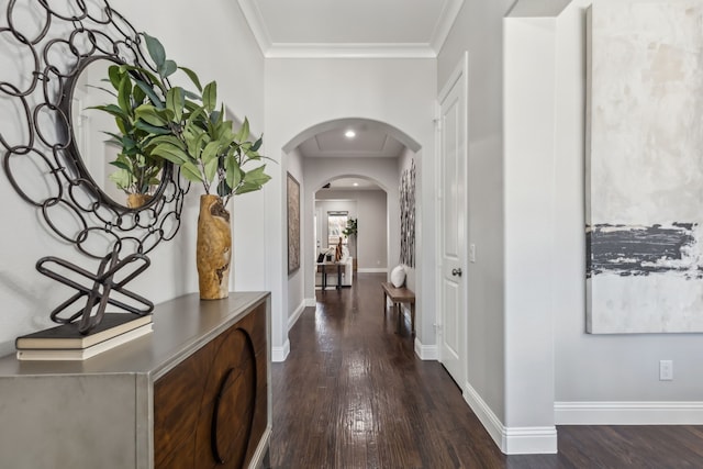 corridor featuring baseboards, arched walkways, ornamental molding, and dark wood-style flooring