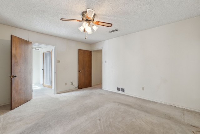 empty room with carpet floors, visible vents, and a ceiling fan