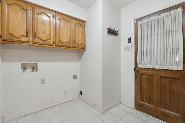 washroom with washer hookup, hookup for a gas dryer, cabinet space, a textured ceiling, and baseboards