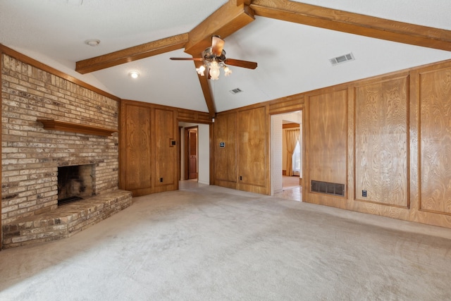 unfurnished living room featuring wood walls, carpet, a fireplace, and visible vents