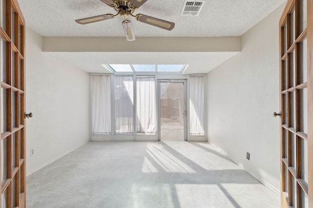 empty room with a textured ceiling, ceiling fan, carpet flooring, visible vents, and french doors