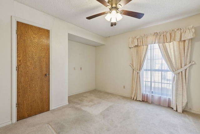 carpeted empty room with a textured ceiling and a ceiling fan