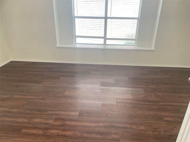 unfurnished room featuring dark wood-type flooring and baseboards