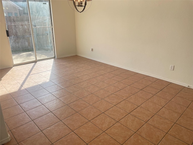 tiled spare room with baseboards and a chandelier