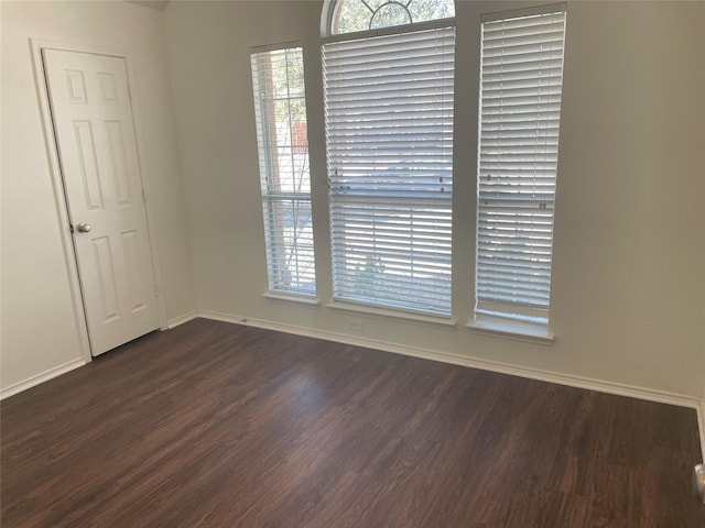 empty room featuring dark wood-style flooring and baseboards