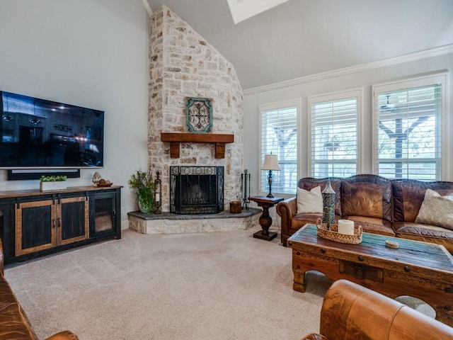 carpeted living area with ornamental molding, a skylight, high vaulted ceiling, and a stone fireplace