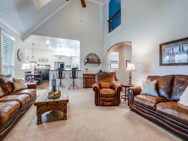 carpeted living area featuring a healthy amount of sunlight, ceiling fan, high vaulted ceiling, and arched walkways