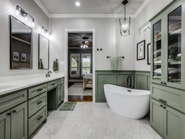 ensuite bathroom featuring a wainscoted wall, ornamental molding, ensuite bathroom, a decorative wall, and a sink