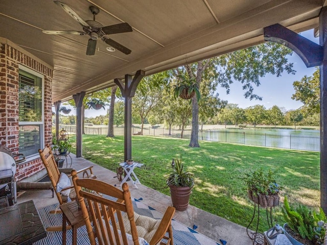 view of patio / terrace with a water view, fence, and ceiling fan