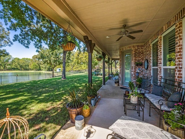 view of patio / terrace with a water view, fence, and a ceiling fan