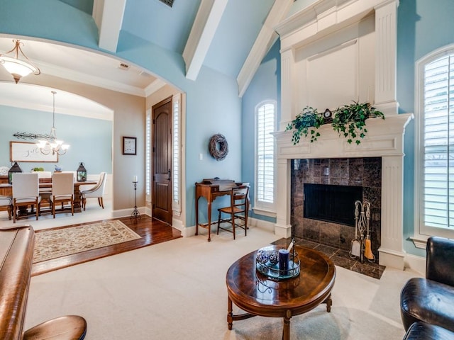 living area with baseboards, arched walkways, ornamental molding, an inviting chandelier, and carpet flooring