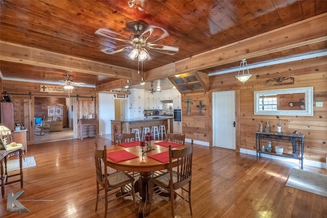 dining area with wooden ceiling, a barn door, a ceiling fan, and wood finished floors