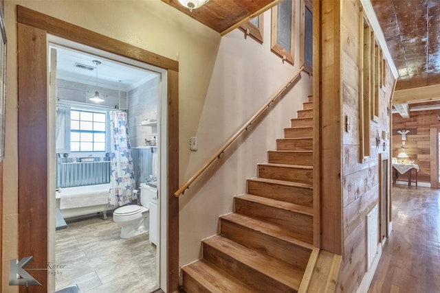 staircase featuring visible vents and wood walls