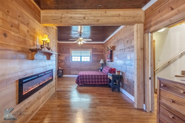 bedroom with a tiled fireplace, wood ceiling, ornamental molding, wood finished floors, and wood walls