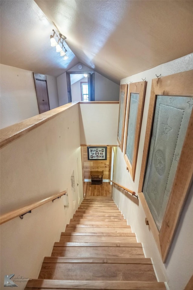 stairway featuring lofted ceiling and wood finished floors