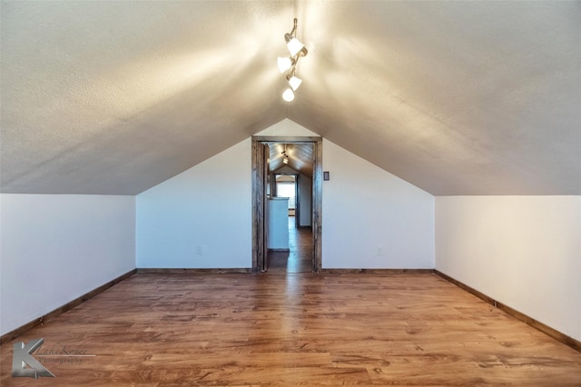 bonus room with a textured ceiling, baseboards, wood finished floors, and lofted ceiling