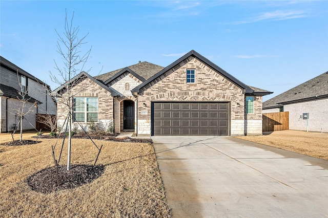 french provincial home featuring driveway, a garage, fence, and brick siding