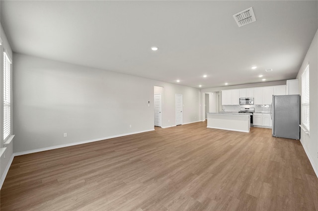 unfurnished living room featuring light wood-style flooring, visible vents, baseboards, and recessed lighting