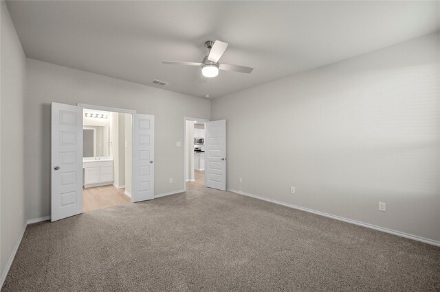 unfurnished bedroom featuring light colored carpet, visible vents, baseboards, and ensuite bathroom