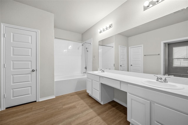 full bathroom featuring double vanity, bathtub / shower combination, a sink, and wood finished floors