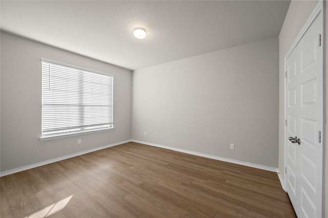 empty room with dark wood-type flooring and baseboards