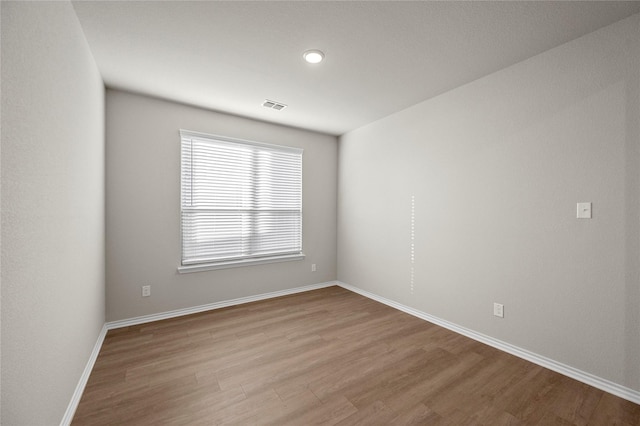 unfurnished room featuring visible vents, baseboards, and wood finished floors