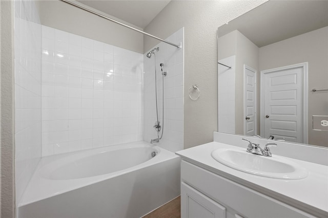 full bathroom with a textured wall, vanity, and shower / bathing tub combination