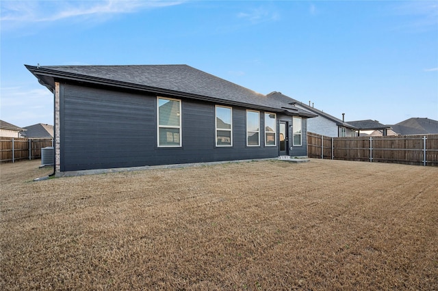 rear view of property with a fenced backyard, a shingled roof, cooling unit, and a yard