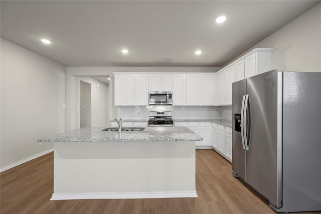 kitchen with light wood-style floors, tasteful backsplash, appliances with stainless steel finishes, and a sink