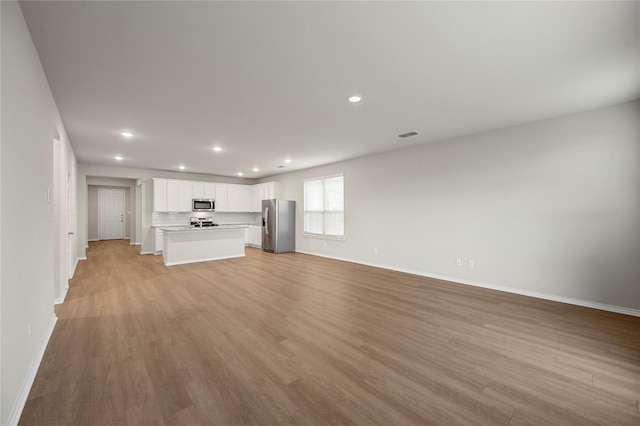 unfurnished living room featuring baseboards, recessed lighting, visible vents, and light wood-style floors