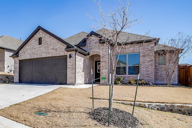 french provincial home featuring roof with shingles, brick siding, fence, a garage, and driveway