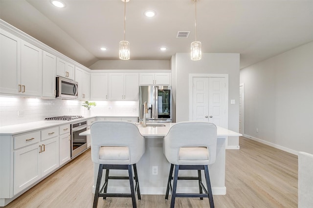 kitchen featuring appliances with stainless steel finishes, light wood-style flooring, backsplash, and visible vents