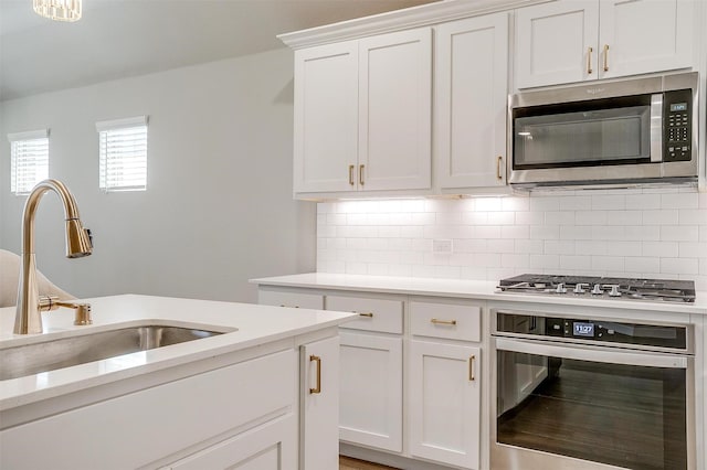 kitchen with appliances with stainless steel finishes, light countertops, a sink, and decorative backsplash