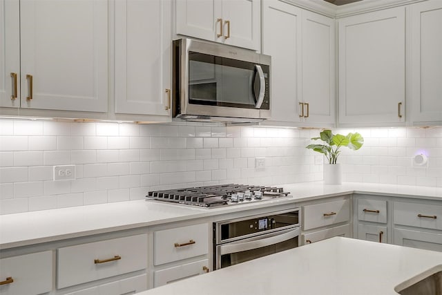 kitchen with white cabinetry, appliances with stainless steel finishes, light countertops, and decorative backsplash