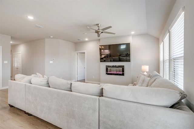 living room featuring a glass covered fireplace, visible vents, light wood-style flooring, and recessed lighting