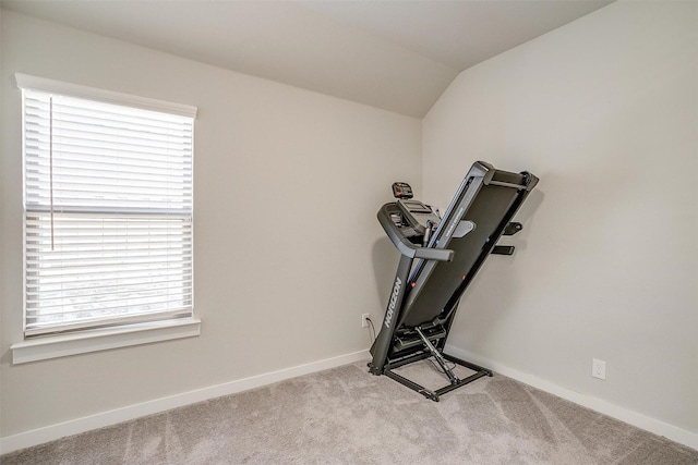 exercise area featuring carpet floors, lofted ceiling, a healthy amount of sunlight, and baseboards