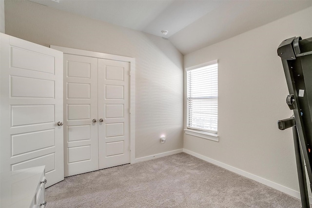 unfurnished bedroom with carpet, baseboards, vaulted ceiling, and a closet