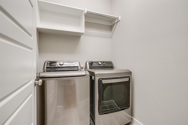 washroom featuring laundry area, separate washer and dryer, and baseboards