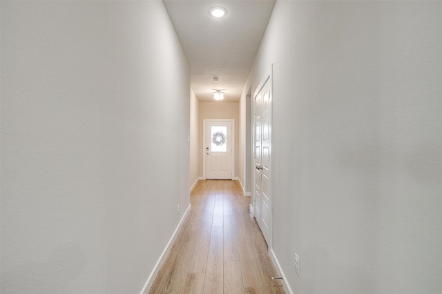 hallway with light wood-type flooring and baseboards