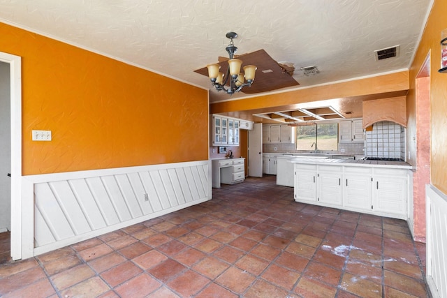 kitchen with wainscoting, a notable chandelier, visible vents, and a textured ceiling