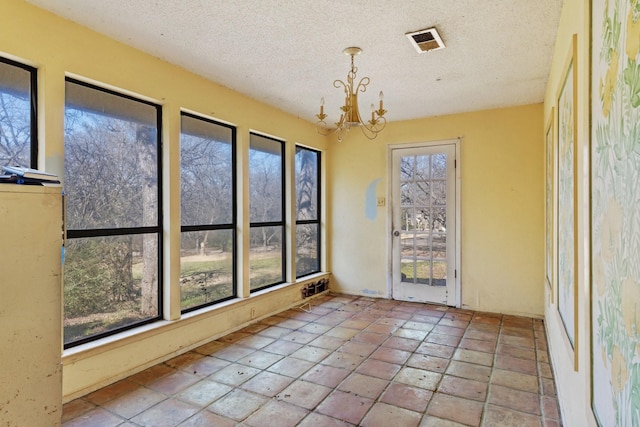 spare room featuring a textured ceiling, visible vents, and a notable chandelier