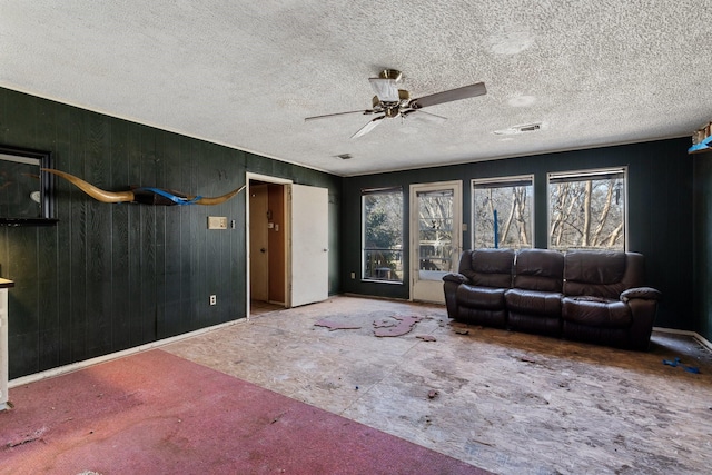 living room with a ceiling fan, visible vents, and a textured ceiling